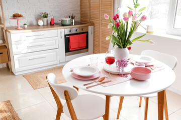 Dining table with setting for International Women's Day celebration in light room interior