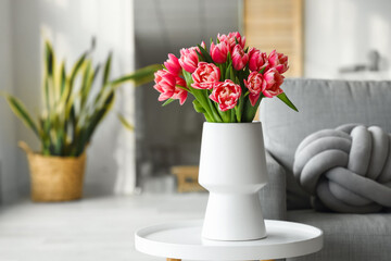 Vase with tulip flowers on small table in living room