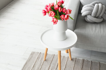Vase with tulip flowers on small table in living room