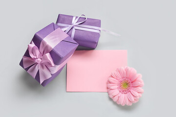 Blank greeting card for International Women's Day, gift boxes and gerbera flower on grey background
