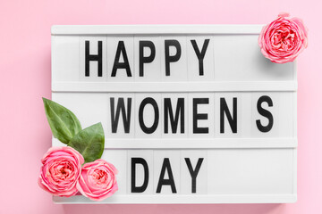 Board with text HAPPY WOMEN'S DAY and roses on pink background