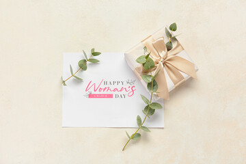 Greeting card with text HAPPY WOMEN'S DAY, gift box and eucalyptus branches on light background