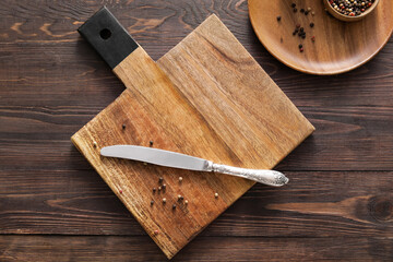 Cutting board and knife on wooden background