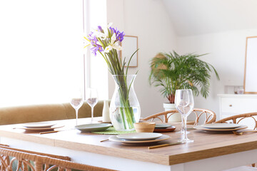 Dining table with setting and beautiful iris flowers for International Women's Day celebration in room