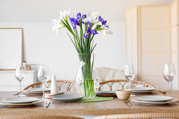 Dining table with setting and beautiful iris flowers for International Women's Day celebration in room