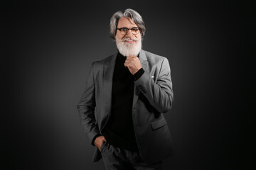 Fototapeta premium Portrait of handsome mature bearded businessman on dark background