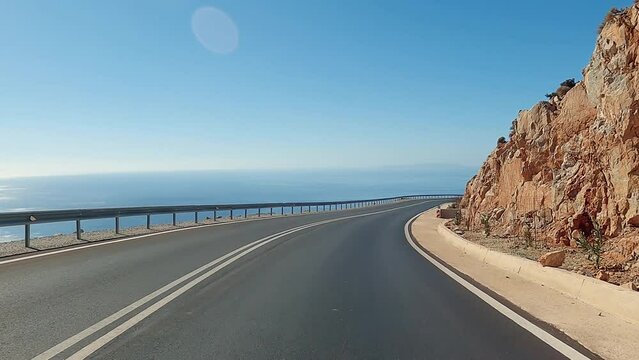 POV shot of the car driving near coast, picturesque landscape, vehicle riding on a coastal mountain national road, sea waves washing rocky coast, vacation adventure, travel