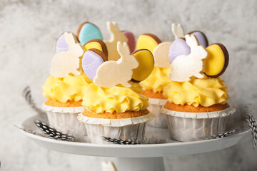 Stand with tasty Easter cupcakes on light background, closeup