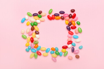 Frame made of multicolored jelly beans on color background