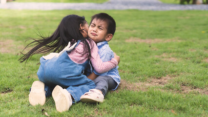Asian sister is hugging and soothing crying little brother to make him feel better, concept of sibling kid, love, relation, friendship and growth of children in family life.