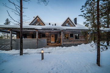 Wooden cabin in the remote forest, with snow covered woods and trees landscape in Lapland, Finland,...