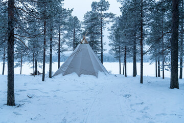 Kota bell tent in the forest for luxury camping and glamping in a winter wonderland snow covered landscape in Lapland, Finland, Arctic Circle