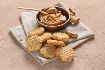 Tasty peanut cookies and butter on beige background