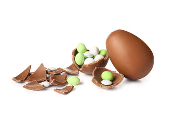 Broken chocolate Easter eggs with candies on white background
