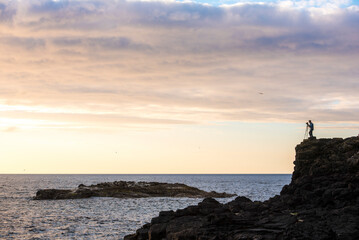 Landscape Photographer silhouette on the dramatic coast, photographing the ocean, County Antrim in Northern Ireland, background with copy space