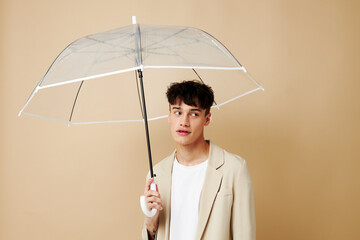 a man with an open umbrella in a jacket protection from the rain beige background