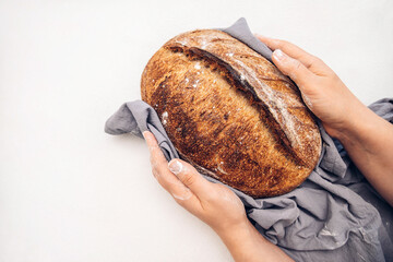 homemade bread in hands. whole grain fresh bread for breakfast. round loaf of bread on a dining...