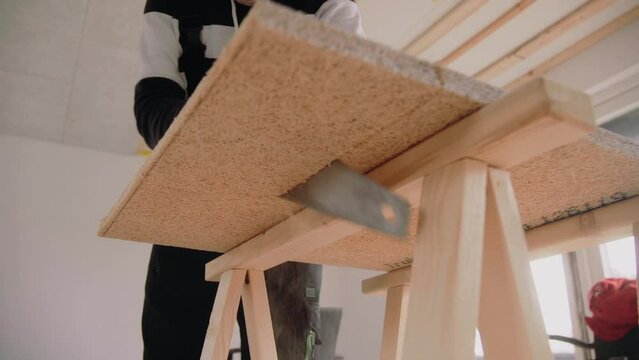 Looking up on a handyman using a handsaw to cut an acoustic panel for the ceiling House Renovation DIY 4K