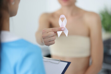 Female show white ribbon sign, symbol for breast cancer