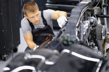 Concentrated serious handyman with tool fix damaged motorbike in garage