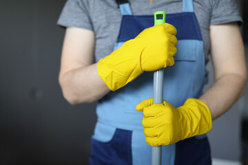 Man holding handle of mop, guy doing domestic work, cleaning at home