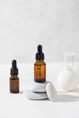 Brown droppers with cosmetics on a pedestal of stones and vacuum cupping massagers in the background.