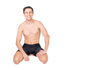 Cheerful shirtless sportsman sitting in light studio