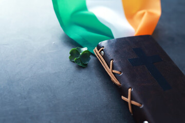 A leather-bound Bible on the table. Religious Christian Irish celebration. Four-leaf clover symbol...