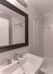 Vertical Interior of a small bathroom with framed mirror above the sink with widespread stainless faucet