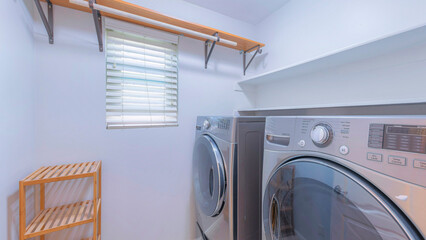 Panorama Small white laundry room interior with wooden shelves and floor rack