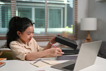 Asian school girl studying online with computer laptop at home.