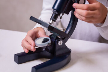 A schoolgirl with a microscope examines chemicals in test tubes, conducts experiments. The concept...