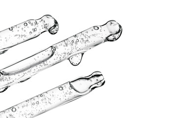 Three transparent pipettes with cosmetics on a light background.