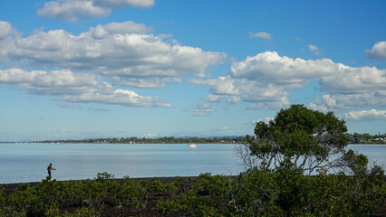View across Moreton Bay from Victoria Point toward Redland Bay, with a single fisherman in the foreground. 