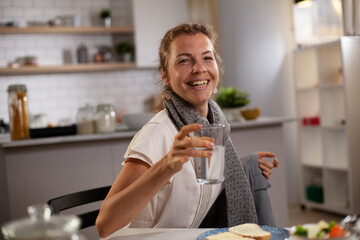 Beautiful businesswoman enjoying in breakfast. Happy young woman eating sandwich at home