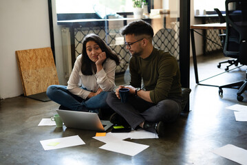 Colleagues in office. Businesswoman and businessman sitting on the floor. Colleagues working on the project