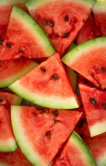background texture of pieces of watermelon in the form of triangles with bones that completely fill the frame, juicy ripe and delicious watermelon