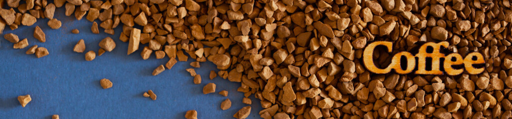 Close-up granular instant coffee on a flat lay with copy space. Word Coffee in wooden letters. Fragrant morning in a coffee shop.