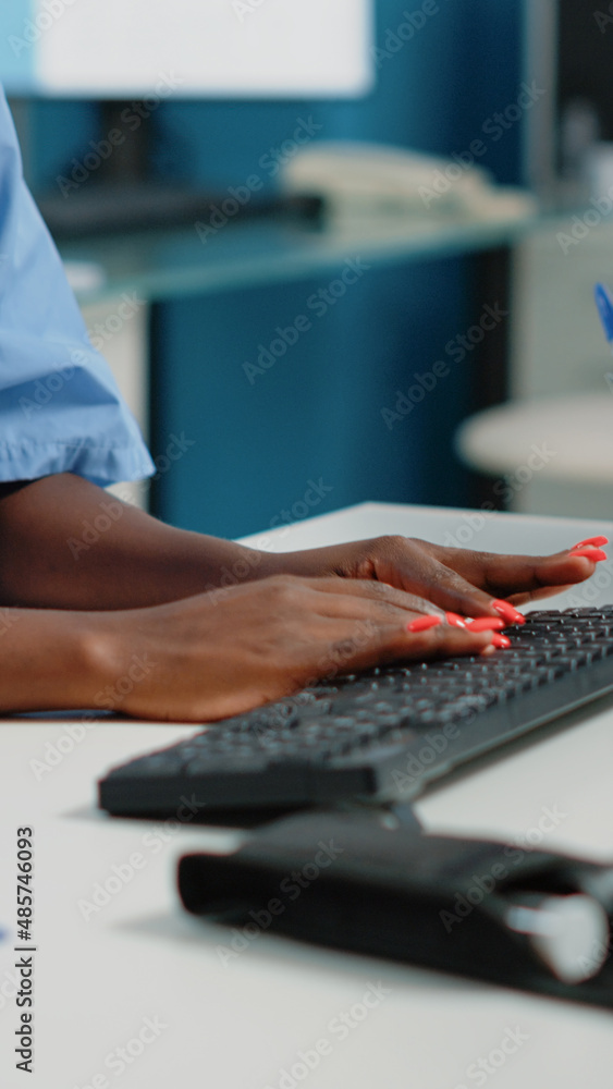 Poster close up of medical assistant typing on computer keyboard in cabinet for appointments with patients.