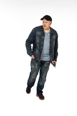 Man on white. Portrait of man with mobile phone in his hands. Guy is walking in denim casual clothes. Human walks and keeps his hand in his pocket. Walking adult male isolated. Guy in cap.