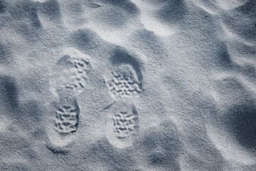 The imprint of two shoes on the sand, resembling the surface of the moon