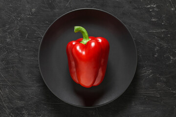 Pepper red sweet, on gray round plate on dark background, top view, with space to copy text.
