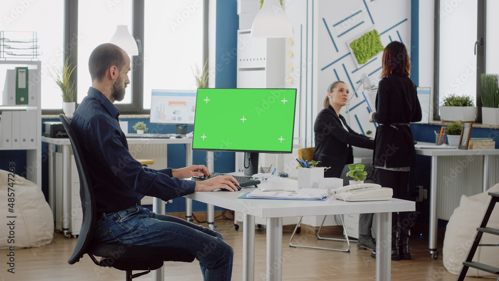 Poster businessman using keyboard and horizontal green screen on monitor at company office. man with corpor