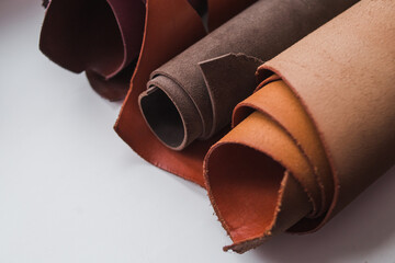 Rolls of genuine brown leather on a white background. Materials for leather goods. Manufacturing of leather goods