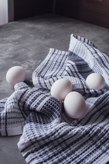 White chicken eggs lie on a white and blue napkin. Gray background. Easter preparations