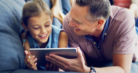 Lessons from dad in online safety. Shot of a cute little girl using a digital tablet with her father on the sofa at home.