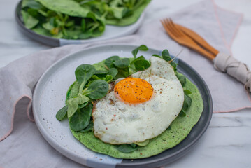 Delicious spinach crepes green colored pancake with vegetables on a table