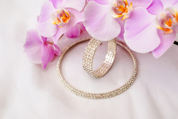Bracelet and necklace on white fabric and purple Orchid
