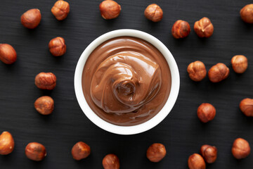 Homemade Chocolate Hazelnut Spread in a Bowl on a black surface, top view. Flat lay, overhead, from...
