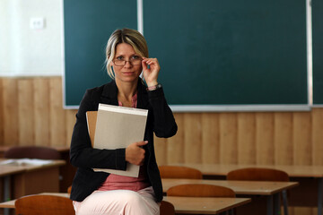 A Happy teacher with books in classroom room back to school